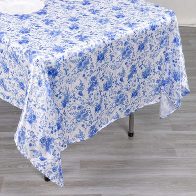 Blue floral tablecloth draped over a table with a wood floor background.