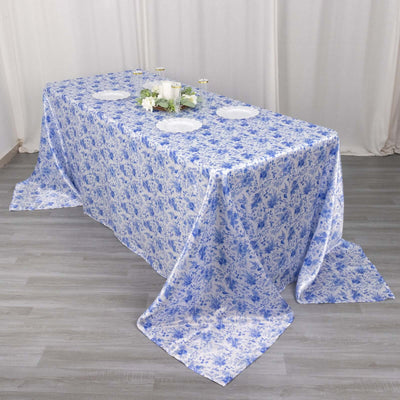 Blue floral tablecloth on a dining table with decorative plates and candles.