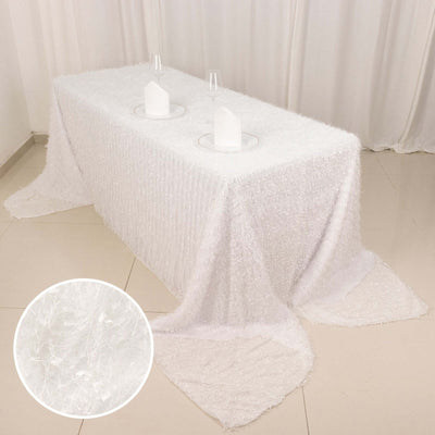 White textured tablecloth draped over a table with glasses and plates.