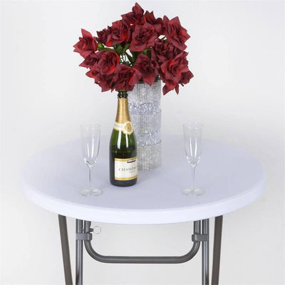 Round table with champagne bottle, glasses, and red flower arrangement