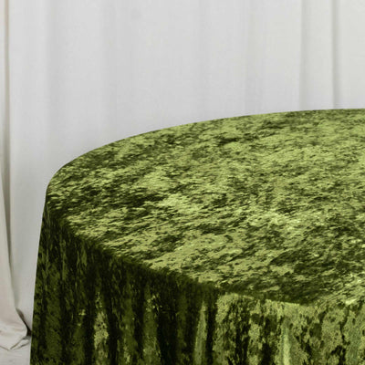 Green velvet tablecloth on a round table with a white curtain backdrop