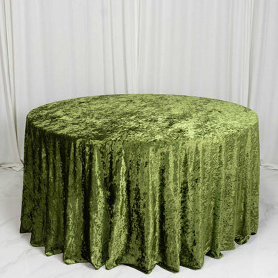 Round table with green velvet tablecloth against white draped backdrop