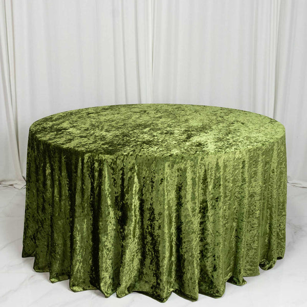 Round table with green velvet tablecloth against white draped backdrop