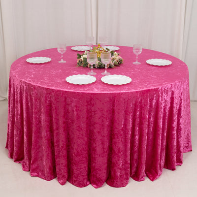 Round pink tablecloth with plates and glasses arranged for dining.