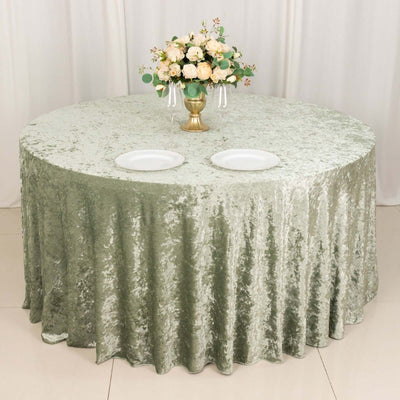 Round green tablecloth with elegant floral centerpiece and dinner plates.