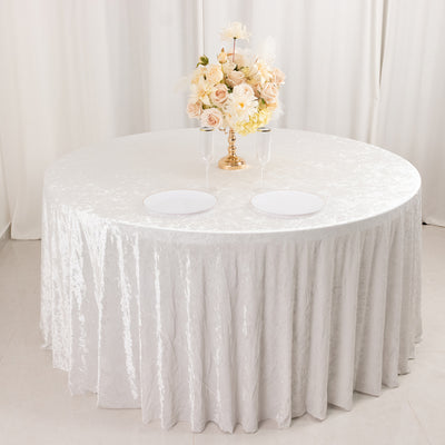 Elegant round table set with white tablecloth, floral centerpiece, and two plates.