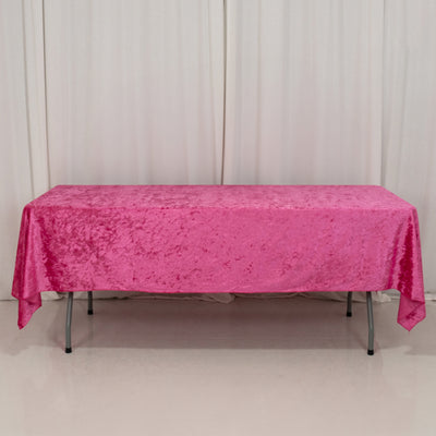 Pink velvet tablecloth on a folding table against a plain backdrop.