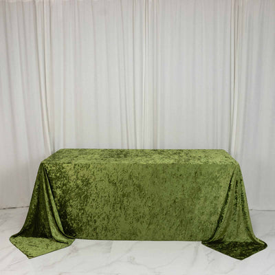 Green velvet tablecloth on rectangular table against white draped backdrop