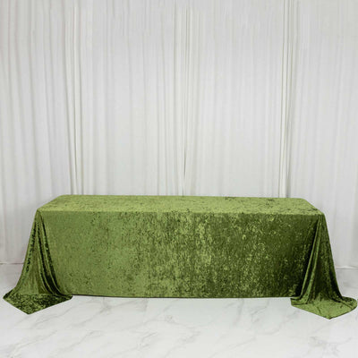 Green velvet tablecloth draped over a rectangular table against white curtains