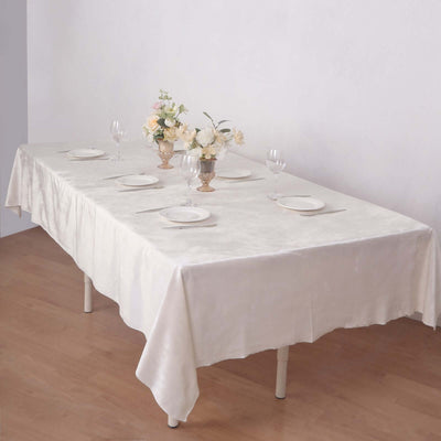 Elegant dining table setting with flowers and tableware on a light tablecloth.