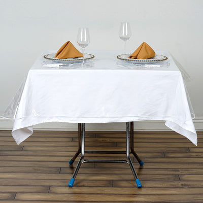 Elegant dining setup with plates, glasses, and napkins on a white tablecloth.