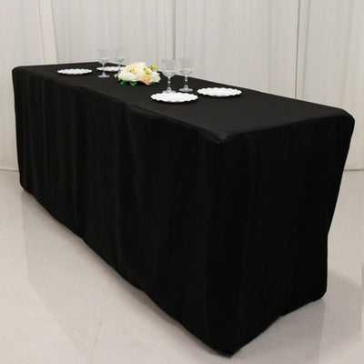 Black tablecloth draped over a table, set with plates and glasses.