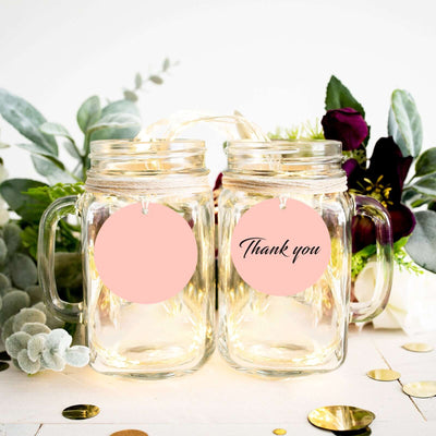 Thank you mason jars with tags, surrounded by greenery and decor.