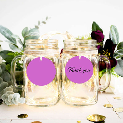 Glass mason jars with "Thank you" tags and decorative greenery.
