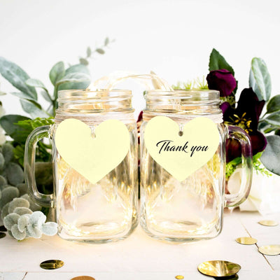 Thank you mason jar mugs with heart tags and decorative greenery.