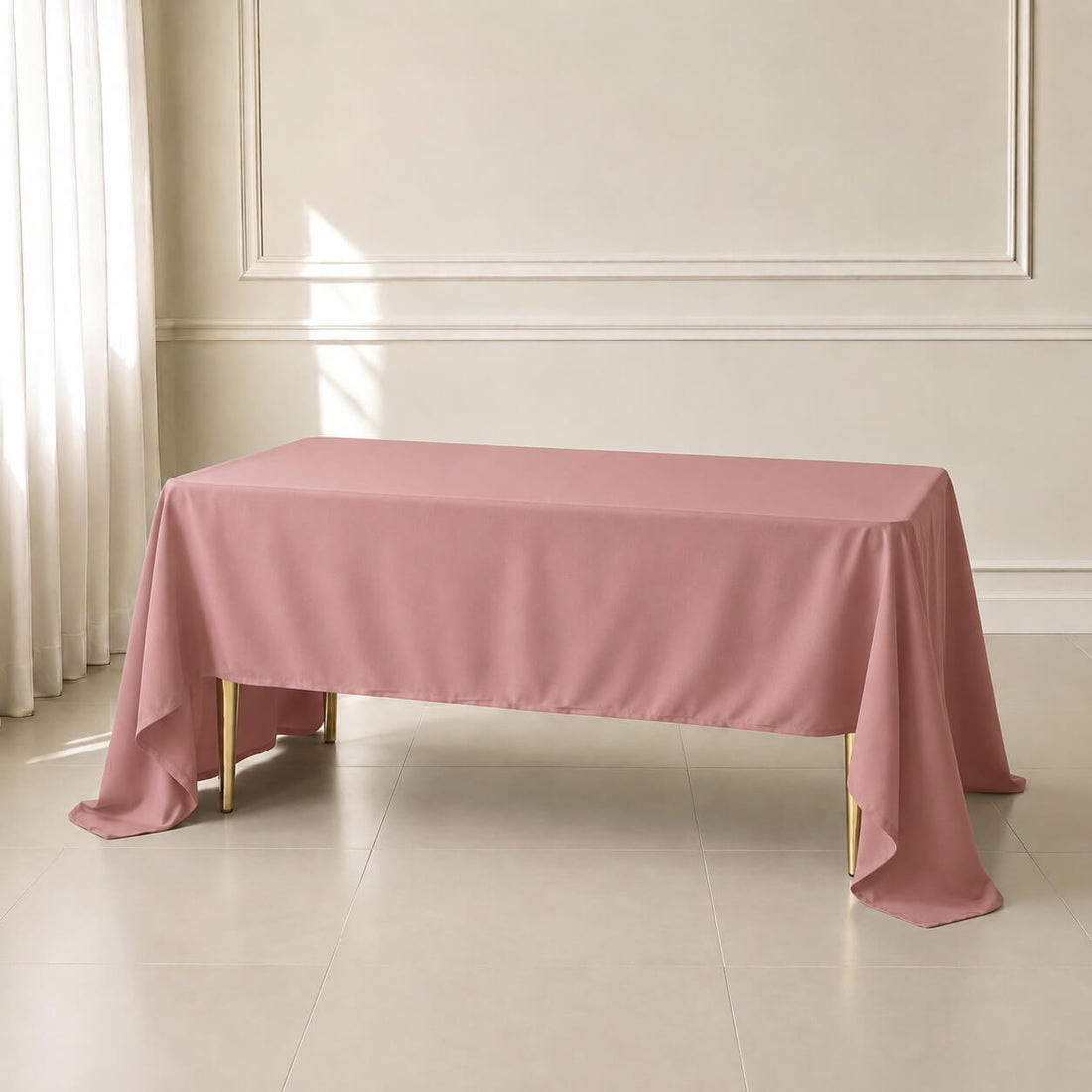 Dusty rose rectangle tablecloth draped over a table in a bright room.