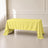 Yellow rectangular tablecloth draping over a table in a bright room.