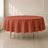 Terracotta round tablecloth on a wooden table in a bright room.