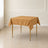 Gold wrinkle-resistant square tablecloth on a table for special occasions.