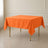 Orange wrinkle-resistant square tablecloth on a table.