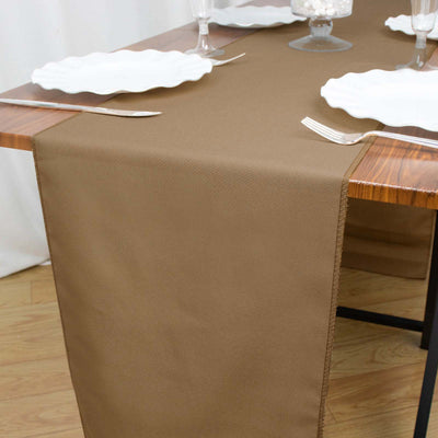 Brown table runner on a wooden dining table set for a meal.