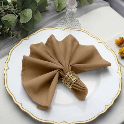 Brown napkin elegantly folded with a gold ring on a decorative plate.