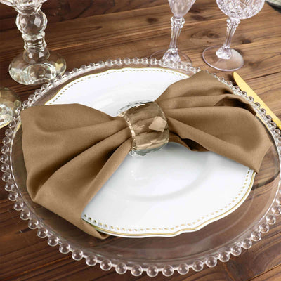 Elegant brown napkin tied with a crystal ring on a decorative plate.