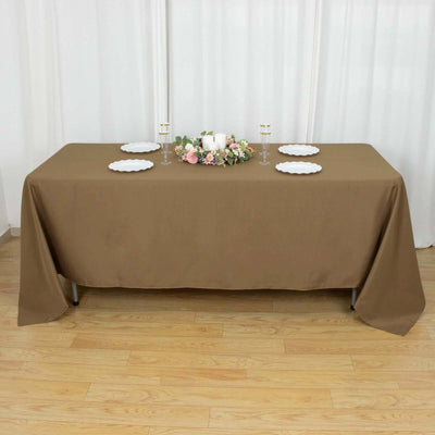 Brown tablecloth draped over a table with floral centerpiece and plates.
