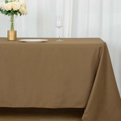 Brown tablecloth draped elegantly on a table with a flower vase and glass.