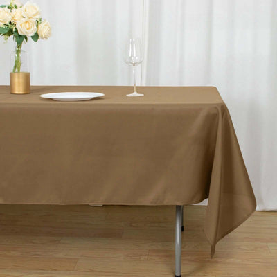 Brown tablecloth draped on a table with flowers and a wine glass.