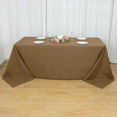 Brown tablecloth draped over a table with plates and floral centerpiece.