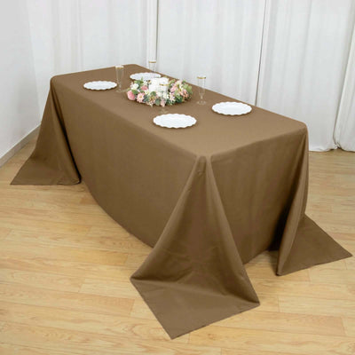 Brown tablecloth draped over a table set with plates and floral decor.