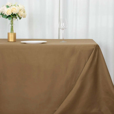 Brown tablecloth draped elegantly on a table with a vase of flowers and glassware.