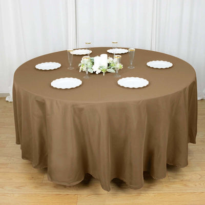 Round brown tablecloth with plates and centerpieces for elegant dining.