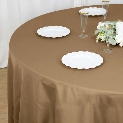 Brown tablecloth draped over a round table set with white plates and glassware.