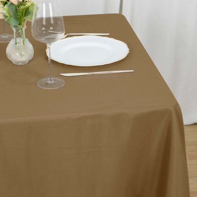 Brown tablecloth draped over a table with a glass and a plate on top.