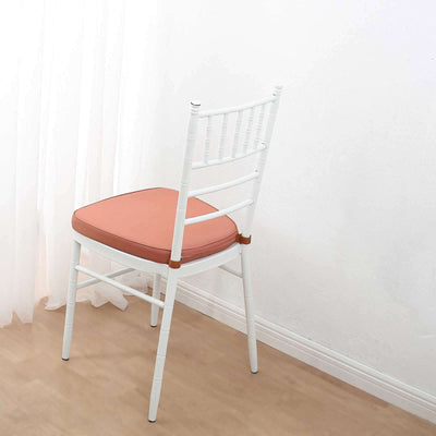 White chair with peach cushion against a plain background.