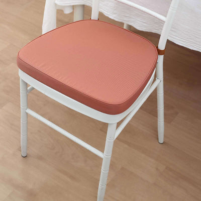 White chair with a coral cushion on a wooden floor.