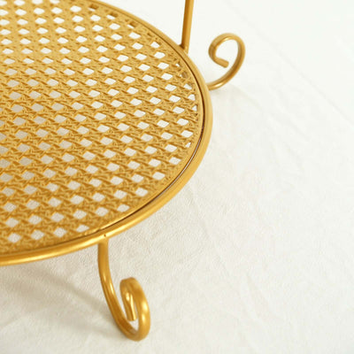 Gold metal cake stand with intricate lattice design and curled legs.