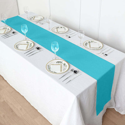 Turquoise table runner on a white table setting with plates and glasses.