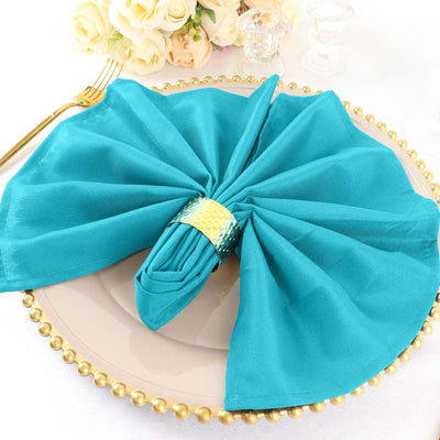 Teal napkin elegantly folded on a gold-rimmed plate.
