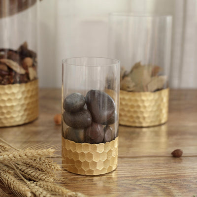 Glass containers with gold honeycomb bases holding decorative stones.