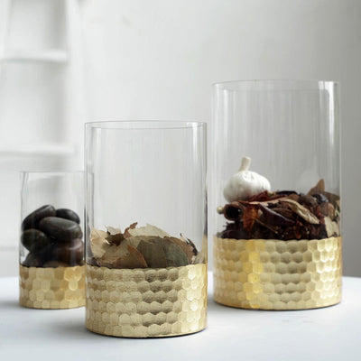 Decorative glass vases with gold honeycomb bases filled with natural elements