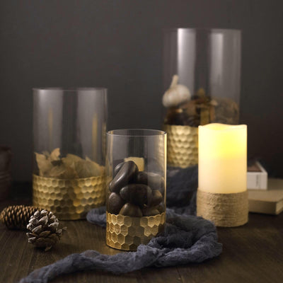 Decorative glass candle holders with gold accents and natural elements.
