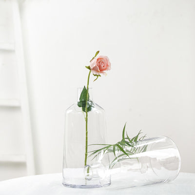 Clear glass vase with a pink rose and green leaves.