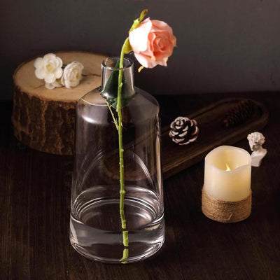 Elegant glass vase with a rose, set on a rustic wooden table.