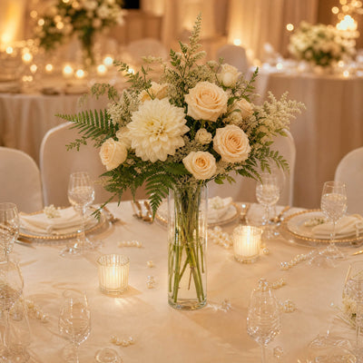 Elegant wedding table centerpiece with white roses, candles, and pearl decor