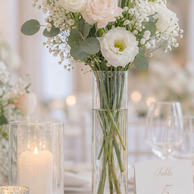 Elegant white floral centerpiece with candle and table number in glass vase