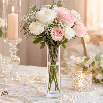 Elegant pastel rose centerpiece in a clear vase with candles and pearls