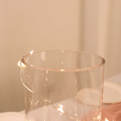 Clear glass vase with warm fairy lights inside.
